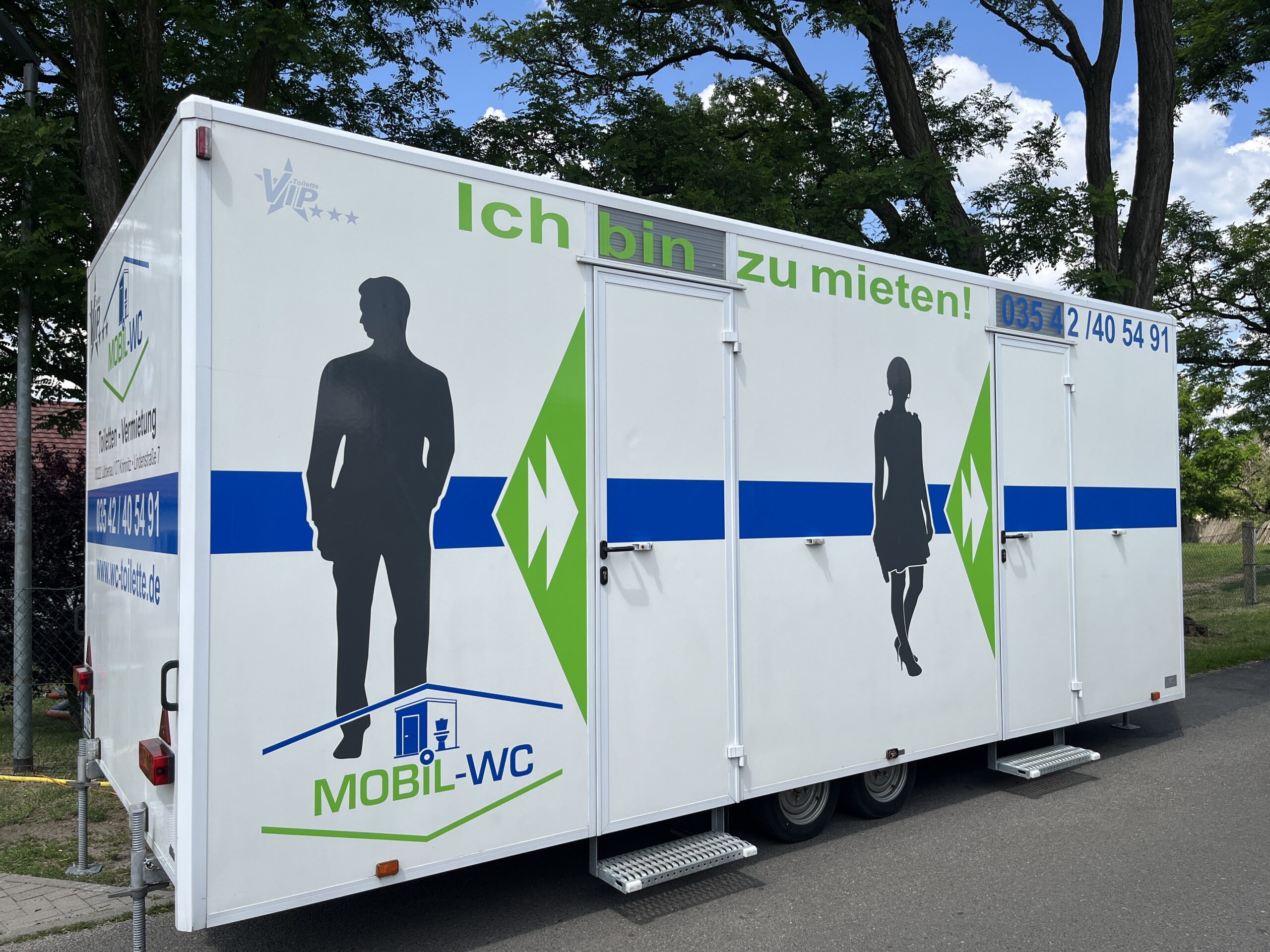 VIP-Wagen von Mobill-WC beim Krimnitzer Dorffest, der seit mehreren Jahren auf dem Festgelände steht. Der Wagen ist dekoriert und von Feiernden umgeben, die die festliche Atmosphäre genießen.